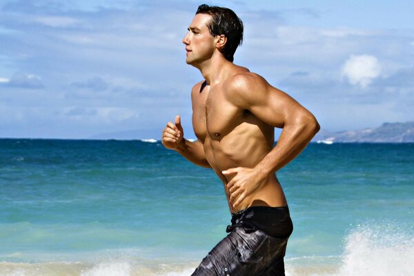 Hombre deportivo corre por la playa