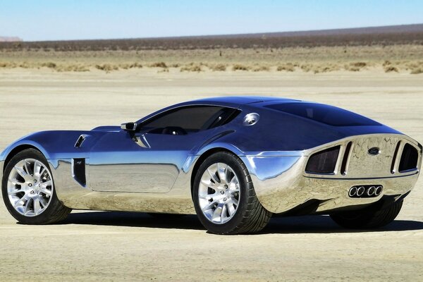 A silver Ford stands in the middle of the desert