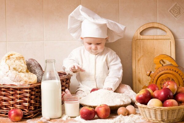 Bebé cocinero en la mesa y la cara en la harina