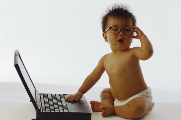 Photo de bébé en lunettes avec ordinateur portable