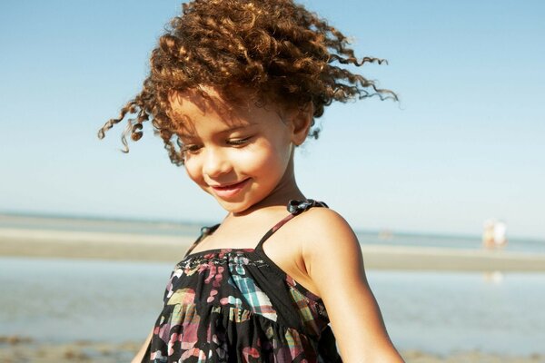 Die Prinzessin des Sommers ist ein lockiges Mädchen am Strand am Meer