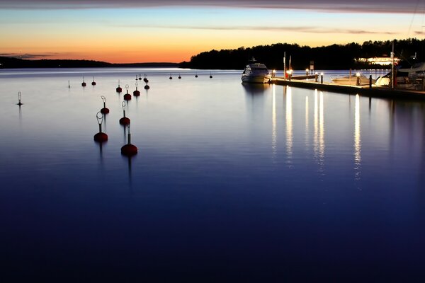 La puesta de sol ilumina la superficie del lago, la costa se refleja en el agua oscura