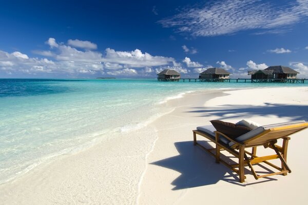 Chaise longue sulla sabbia della spiaggia dalle case al mare