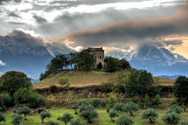 Nuvole temporalesche, alberi e una casa sulla collina