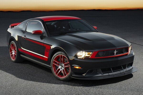 Ford mustang in nero e rosso sullo sfondo del tramonto