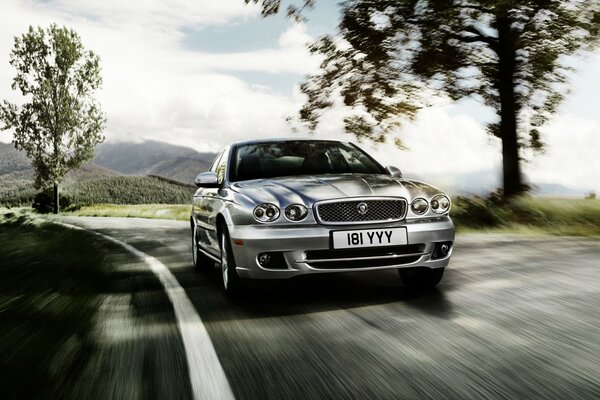 A jaguar car drives along a country road