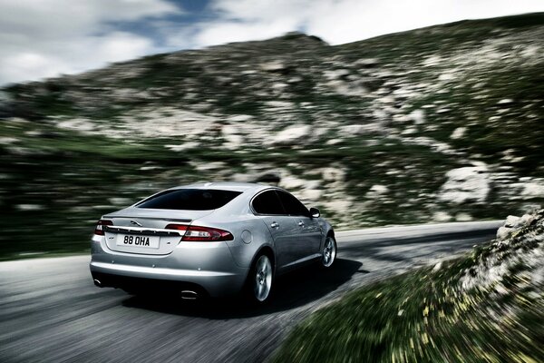 Coche Jaguar conduce a velocidad por carretera de montaña