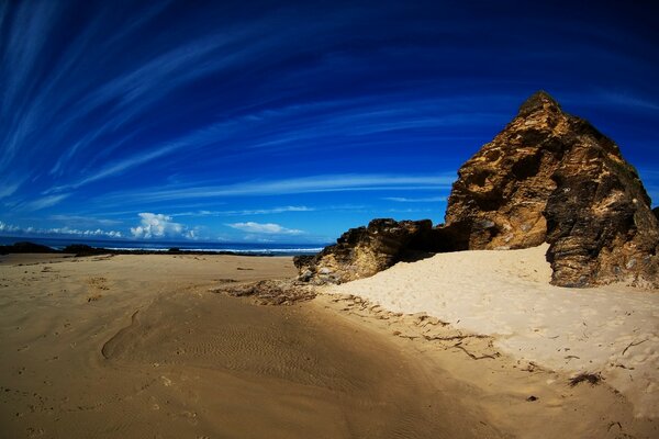 Песчаный пляж со скалой на берегу океана