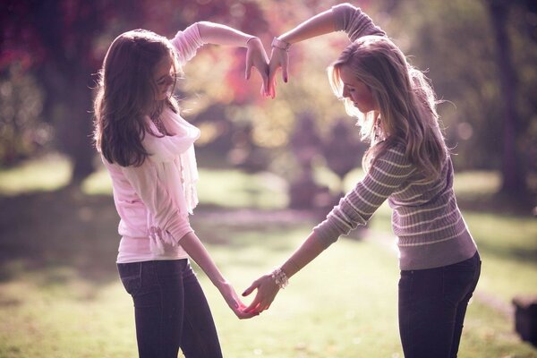 In nature, in a beautiful park, girls make a heart