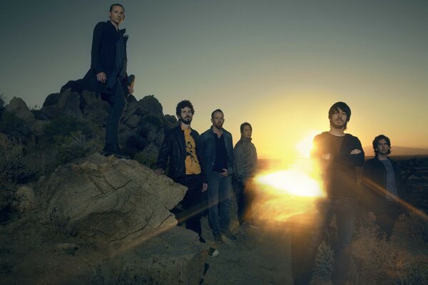 A rock band at sunset takes a group photo