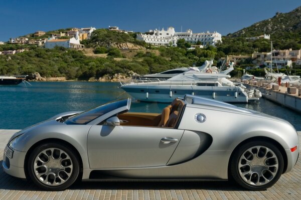 Bugatti is parked on the pier with yachts