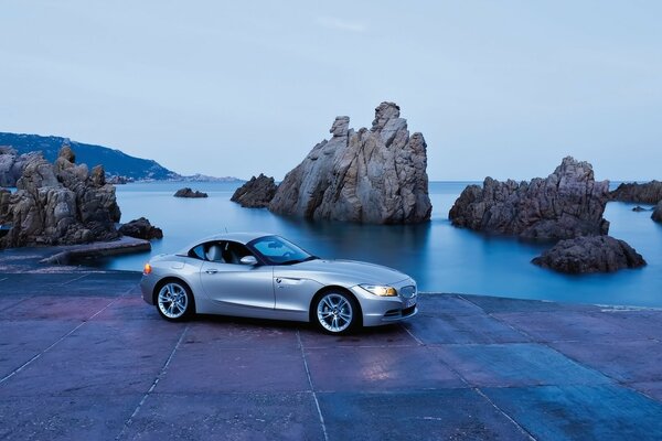 Gray car on a background of rocks and water