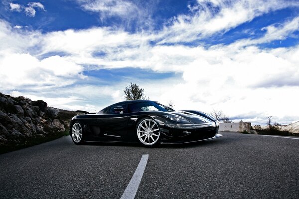 Black sports car on the highway against the blue sky