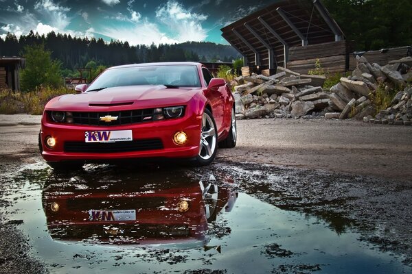 Chevrolet rojo y su reflejo en un charco en el fondo de las montañas