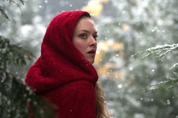 Ragazza in caldo cappotto rosso in inverno nella foresta