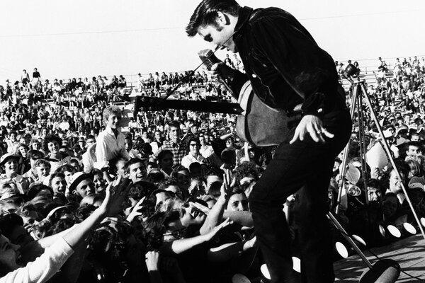 Foto en blanco y negro. Elvis en el escenario frente a la multitud