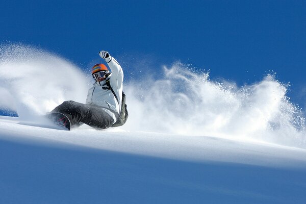 A snowboarder rides down a slope in the snow