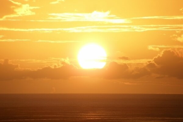 Bright sun at summer sunset by the sea