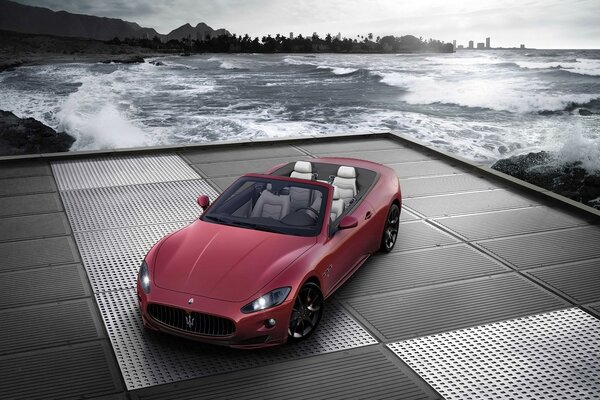 Красный Maserati с откидным верхов у воды