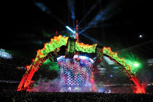 A show at a music festival, an arena filled with an audience, huge scenery on stage