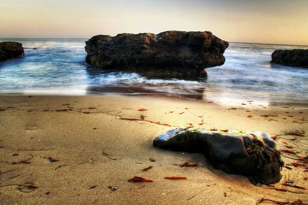 Sunset on the sea with surf through the rocks