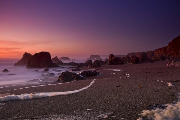 Wilder Strand bei Sonnenuntergang mit Meeresschaum