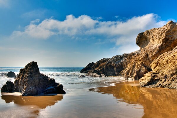 Praia de areia no oceano com blocos de pedra