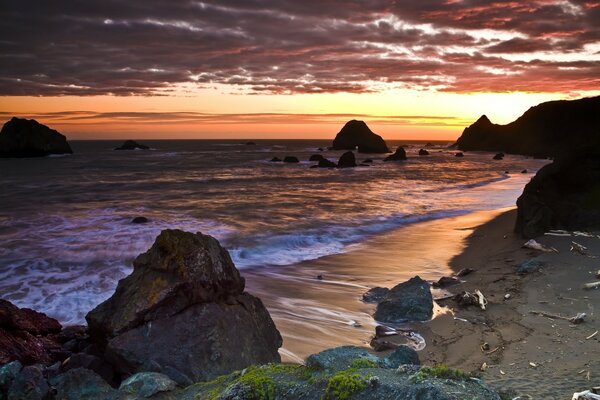 Sunset near the ocean. Evening beach with rocks and waves