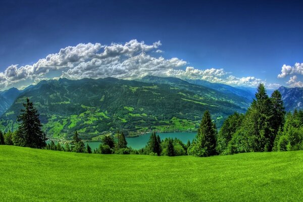 Berglandschaft. Weiße Wolken, eine Alpenwiese und Berge am Horizont