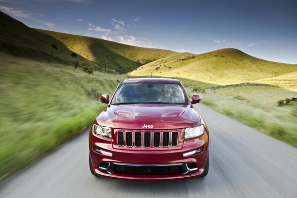 Jeep rojo monta en el asfalto