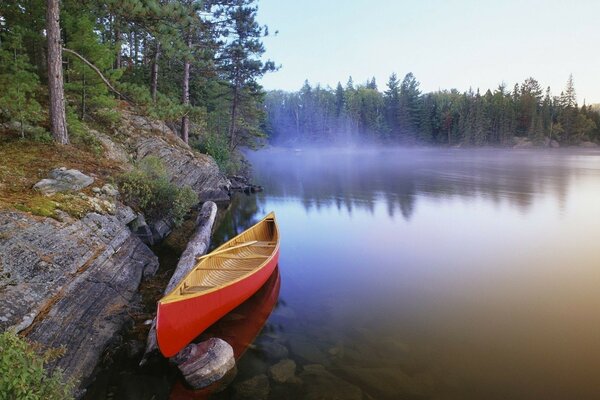 Red boat on the background of the lake and trees