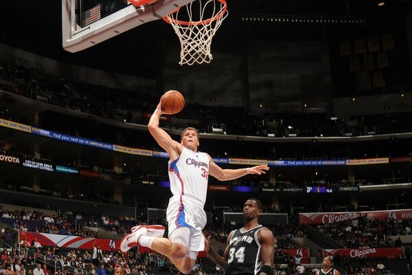 A basketball player throws the ball into the basket