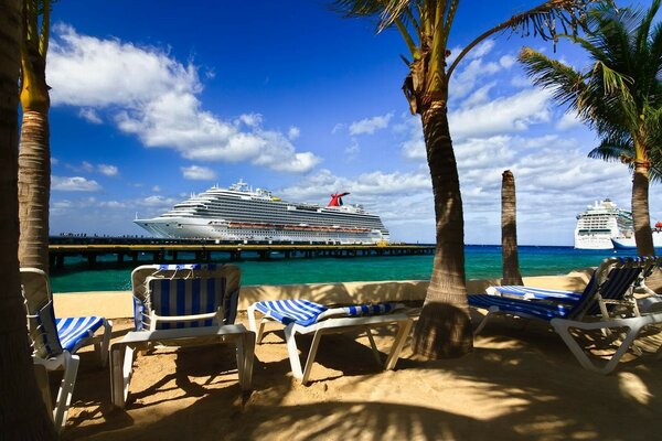 View of the resort beach with a yacht from the shore with sun beds