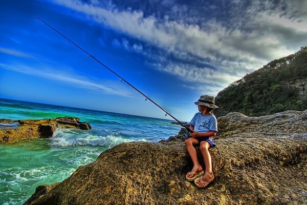 Menino pescando na costa rochosa