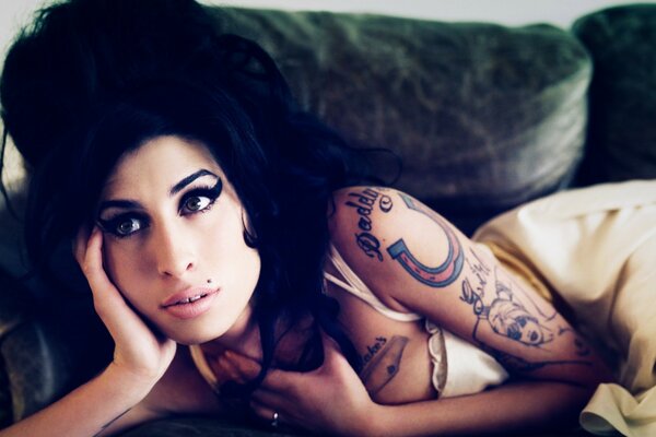 Belle chanteuse avec tatouage sur le lit