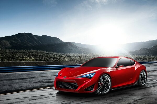 Red sports car in the mountains on the road