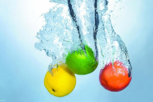 Tres manzanas de diferentes colores que cayeron al agua