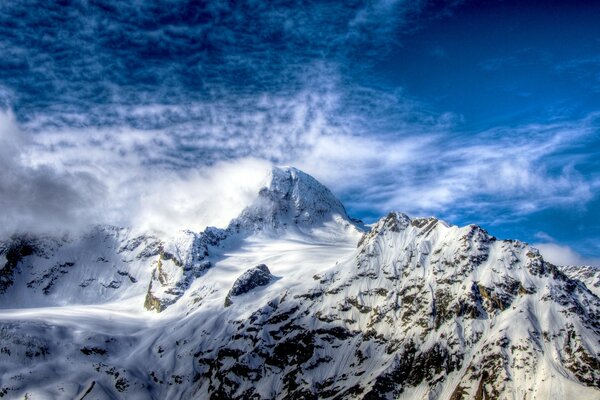 एक नीले आकाश के खिलाफ बर्फ से ढके पहाड़