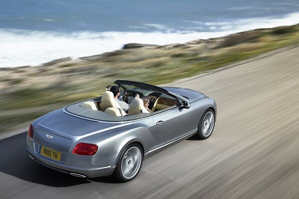 The Bentley is speeding down the road. Near the sea