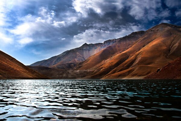 पहाड़ों में झील भारी बादलों से भागने के बाद पानी के माध्यम से चलने वाली छोटी लहरें