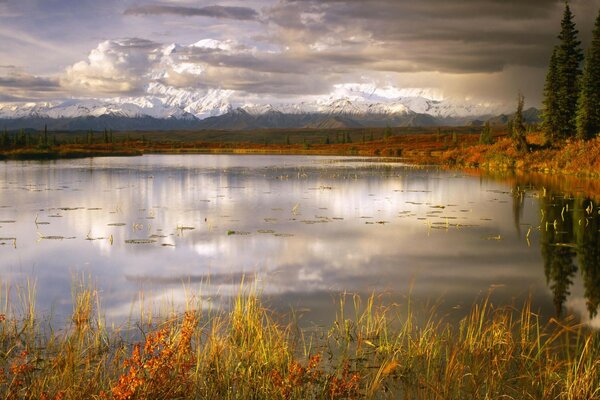 Herbstsee und schneebedeckte Berge am Horizont