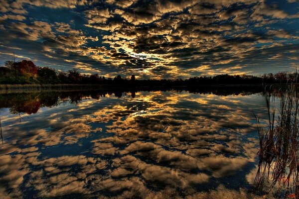 Beautiful sunset through clouds reflected in the lake