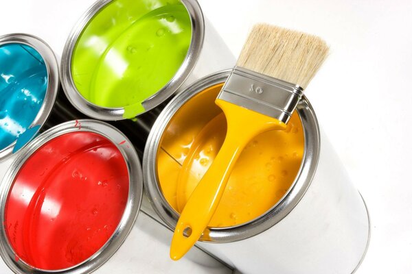 4 pots de peinture de différentes couleurs et un pinceau