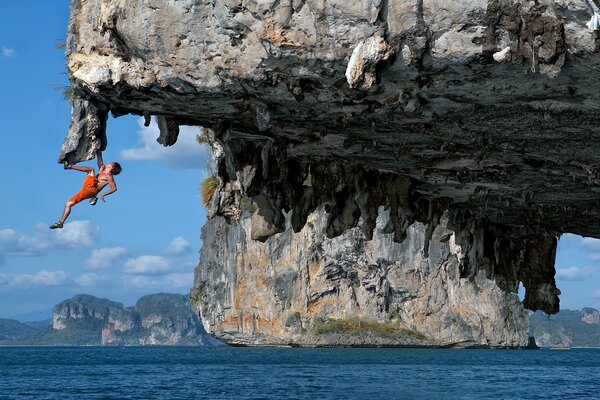 An exciting trick of a young man on a rocky cliff