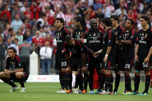 A equipe de futebol de uniforme preto está esperando por algo