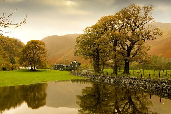 Paisaje con lago, casa y árboles al amanecer