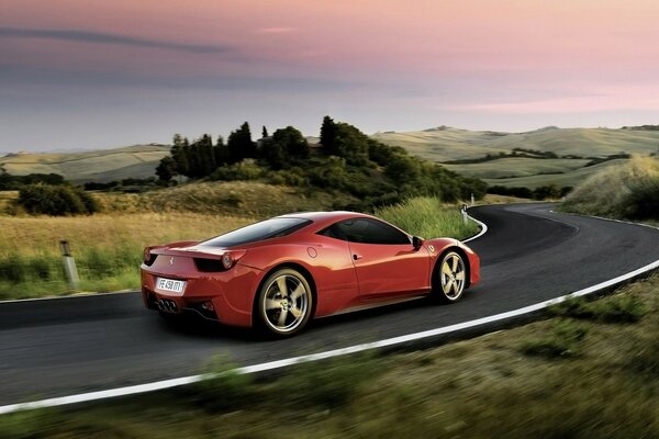 A red Ferrari car racing along the road among the fields