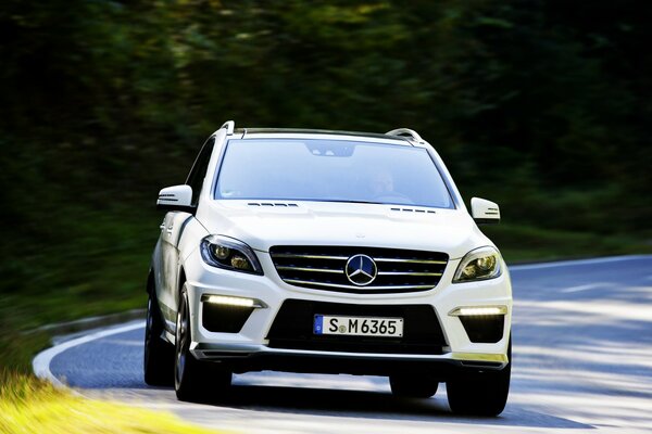 Une voiture blanche mercedes benz se précipite sur une route goudronnée