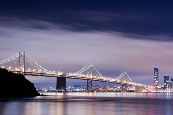 Uma ponte cheia de luzes sobre o rio para a cidade