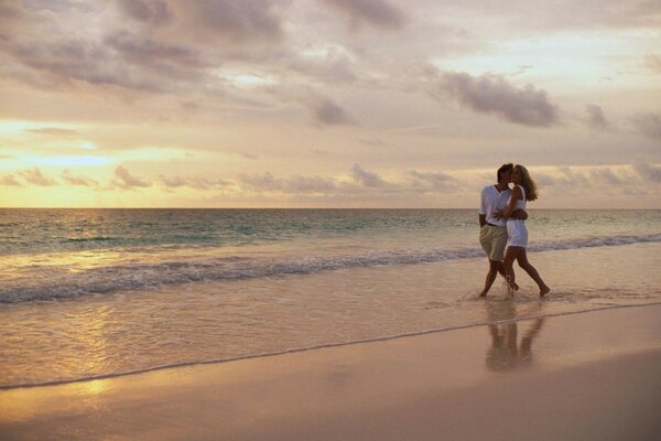 Casal andando na praia ao pôr do sol